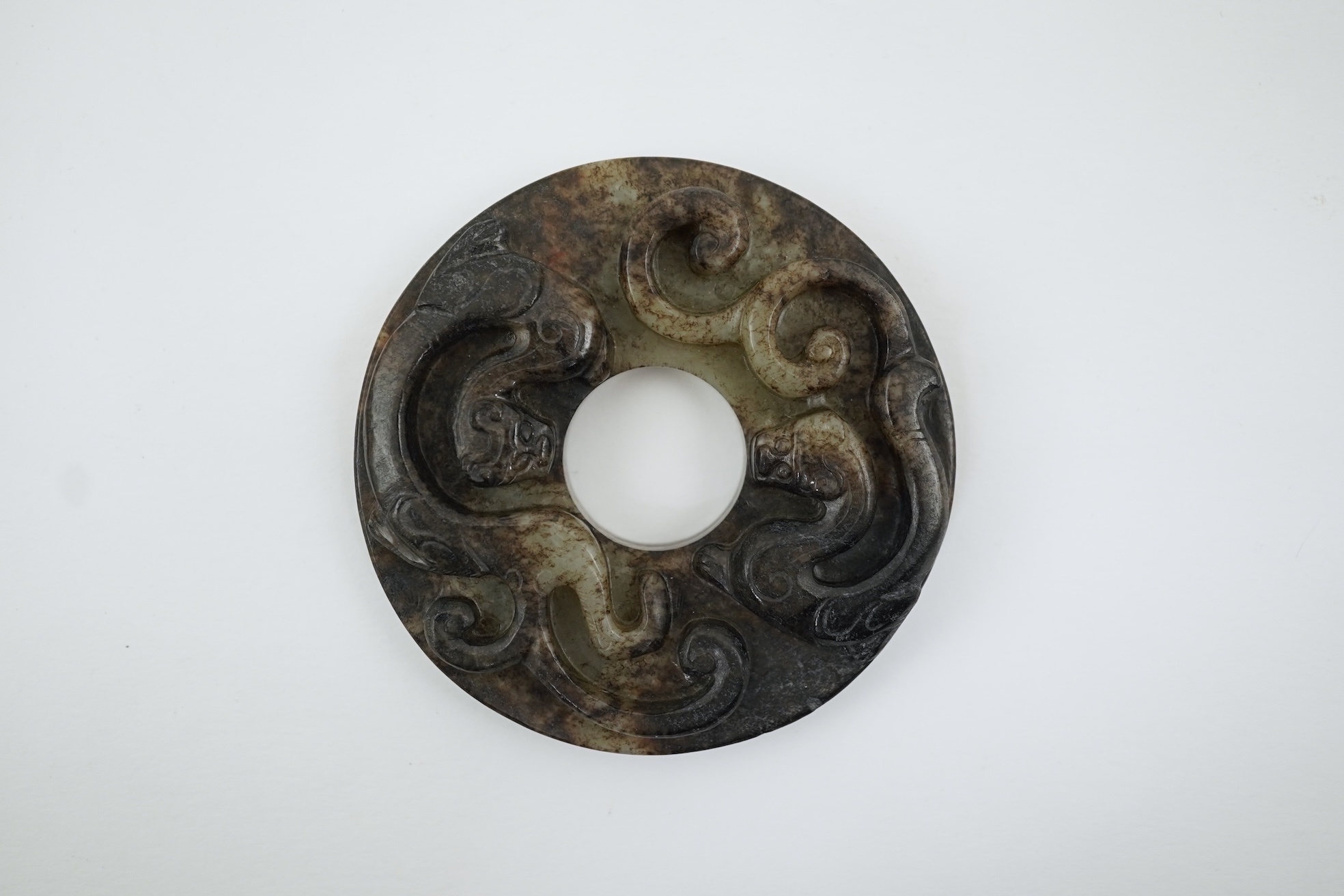 A Chinese pale celadon and black jade bi disc